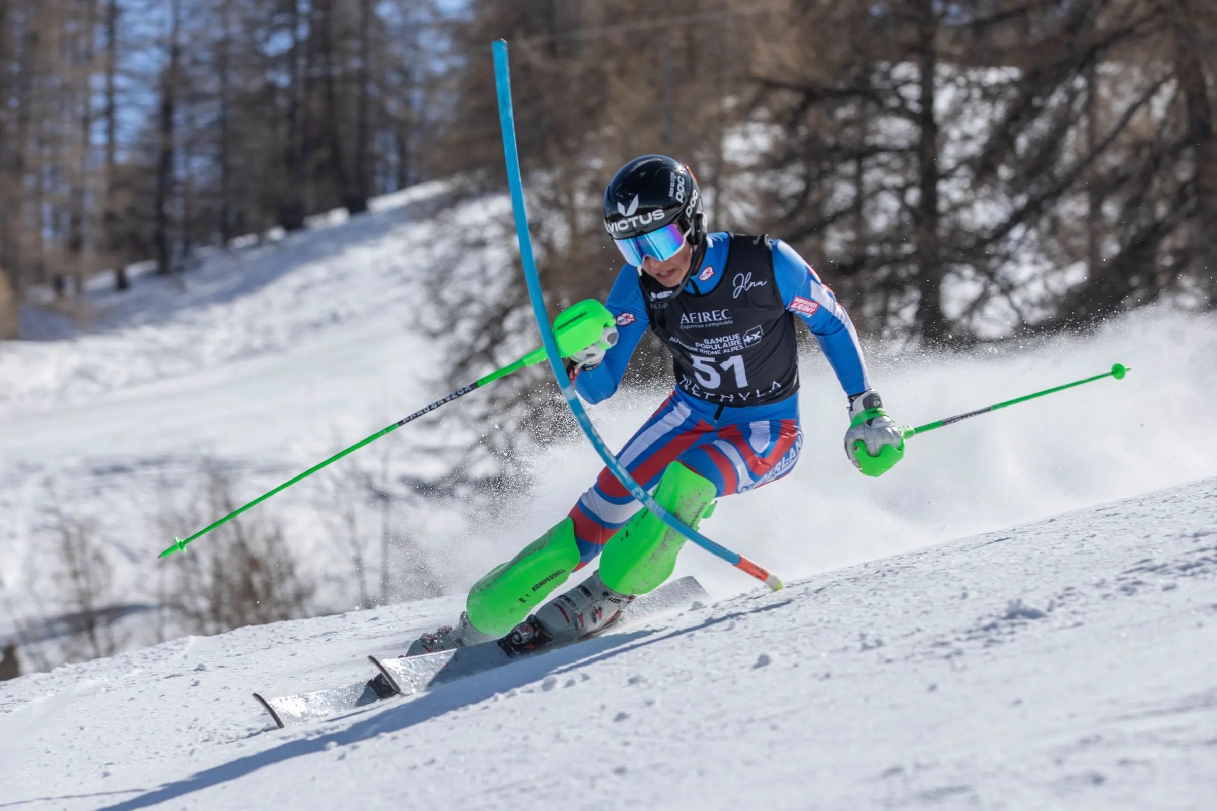 Floris Wondergem rounding a blue slalom gate on a sunlit race piste in the Alps